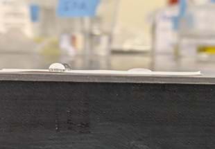 A photo showing a close-up of two pure water droplets and one soapy water droplet on a strip of Teflon tape. A photo showing a close-up of two pure water droplets and one soapy water droplet on a strip of Teflon tape.