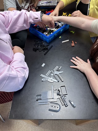 A photo showing students’ arms and hands as they are grouping different types of LEGO pieces. 