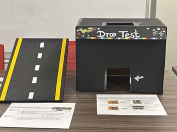 A photo of a quality test site, including a ramp, decorative box with a hole in the top that acts as a drop site, and building guidelines. A photo of a quality test site, including a ramp, decorative box with a hole in the top that acts as a drop site, and building guidelines.