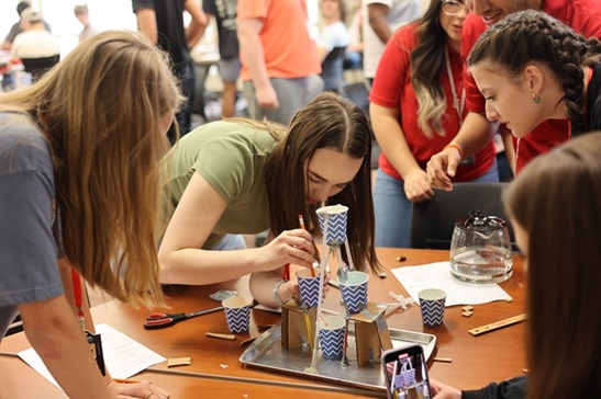 A photo of students working together around a table to build their Gatorade machine.