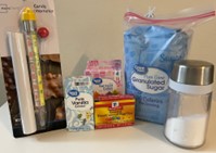 A photo of household items the student will need to perform the at-home experiment, including a bag of pure cane granulated sugar bag, liquid food coloring, vanilla extract, and a candy thermometer.