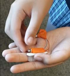 A photo of a student demonstrating the attachment of the toothbrush, motor, and battery.