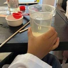 A photo showing a beaker containing saltwater, baby oil, and corn syrup, with a paperclip floating in the mixture.