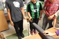 A photo of three students standing in front of a leaf blower holding two anemometers. A photo of three students standing in front of a leaf blower holding two anemometers.