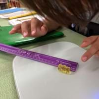 A photo showing a student measuring the length of a gummy with a centimeter ruler. A photo showing a student measuring the length of a gummy with a centimeter ruler.