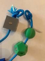 A photo of a blue cord with amino acid models on it and loops on both ends of the strand of amino acids. A photo of a blue cord with amino acid models on it and loops on both ends of the strand of amino acids.